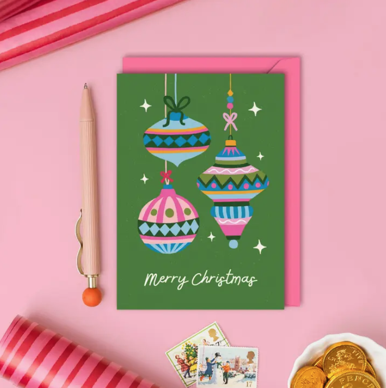 Christmas card with colorful ornaments on a pink background