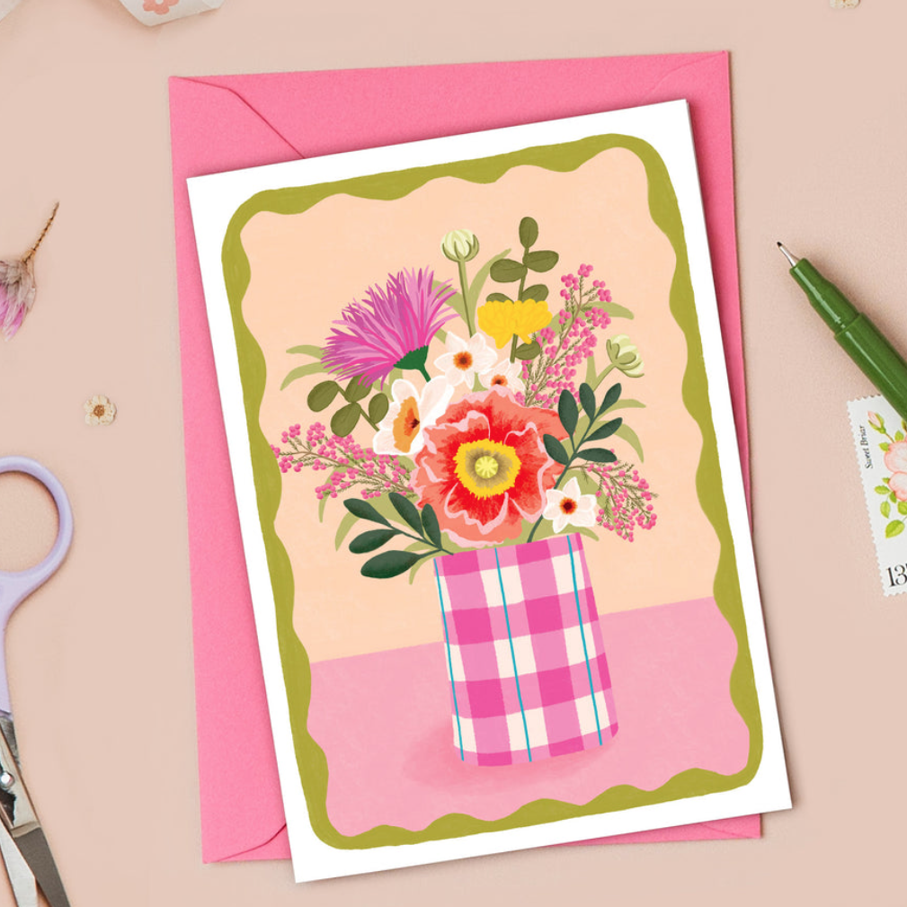 Greeting card with floral design and pink envelope on a beige background