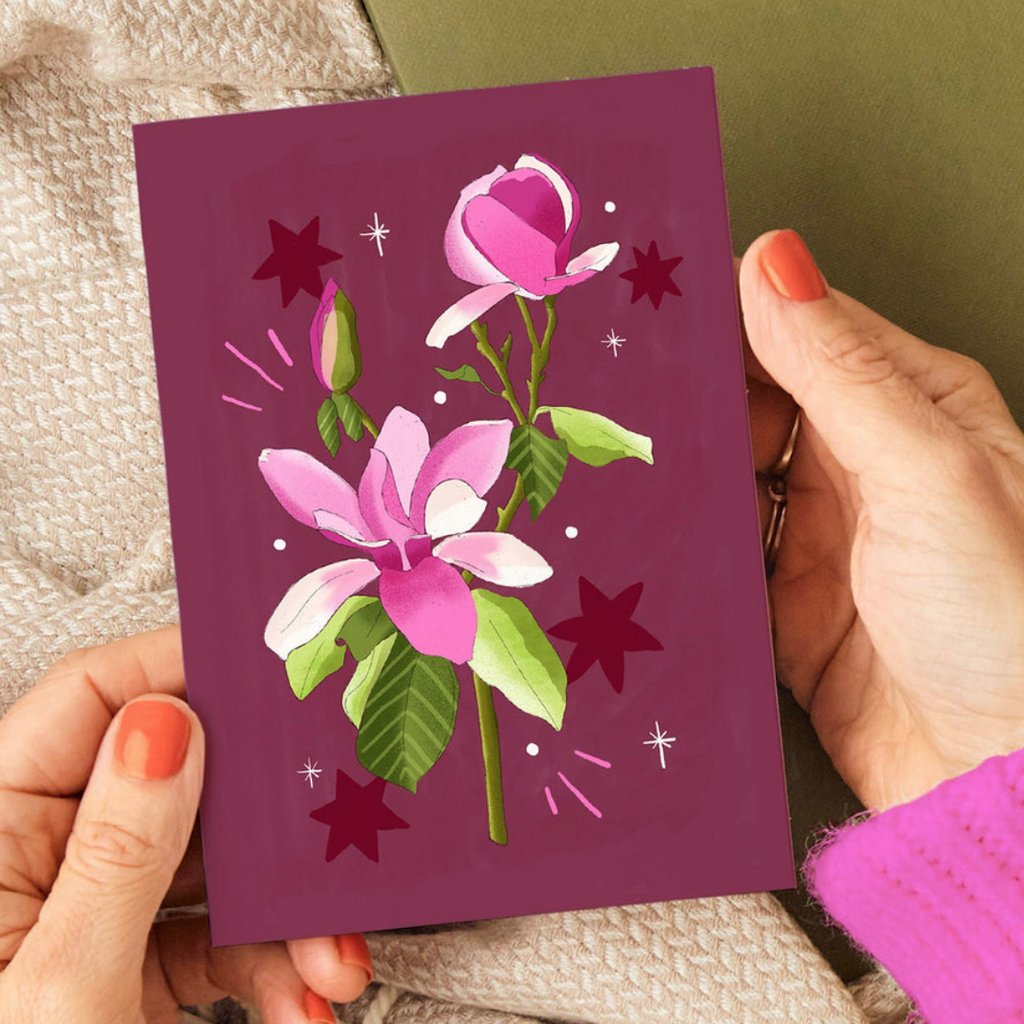 Hand holding a purple card with floral design